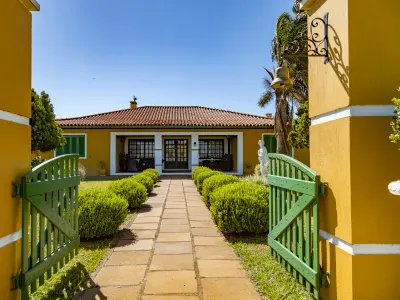 A Casa Principal da Villa, com os portões verdes e o caminho de pedras pelo jardim